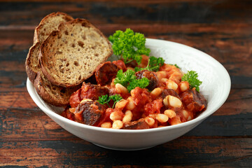 Bean and chorizo stew served in white bowl with parsley