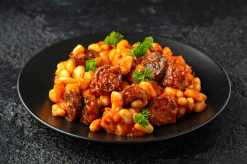 Bean and chorizo stew served in black plate with parsley