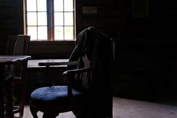 Old jacket hanging on an antique armchair with faded natural light.
