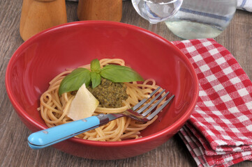 Spaghetti au pesto avec un morceau de parmesan dans une assiette en gros plan