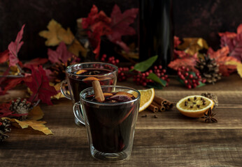 Selective focus of glass with hot mulled wine. Autumn recipe, warm alcohol beverage with spices, cinnamon, and orange.