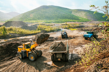 Front loader loads mountain soil into a dump truck bucket. © Letopisec