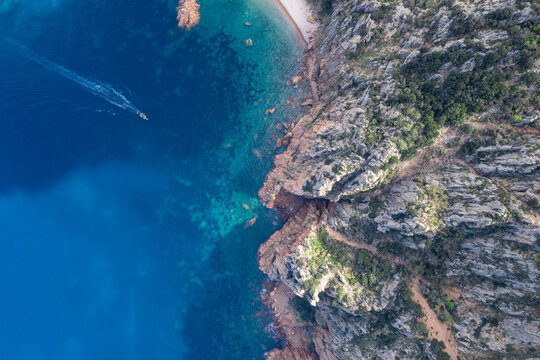 Vue aérienne du Capo Rosso (Capu Rossu) avec un bateau sur une eau turquoise, Corse