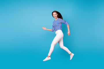 Full length body size profile side view of her she nice attractive slender cheerful cheery girl jumping running going wearing casual isolated bright vivid shine vibrant blue color background