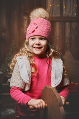 christmas portrait of a happy little girl on a toy horse, wooden swing