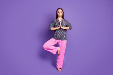 Full length photo of focused girl train yoga workout exercise raise leg put hands together wear pink dotted pajama pants trousers isolated over violet color background