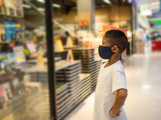 A boy wear a protective mask Looking at the showcase In a bookstore.
