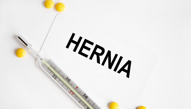 HERNIA - the inscription on the business card, next to the yellow tablets and the thermometer. A medical concept.