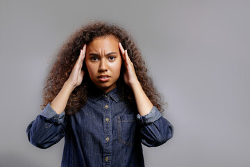Portrait of young beautiful black woman standing over isolated grey background showing emotions. Female with emotional facial expression. Close up, copy space.