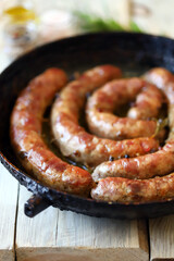 Selective focus. Fried homemade sausages in a frying pan on a wooden table. Rustic style.