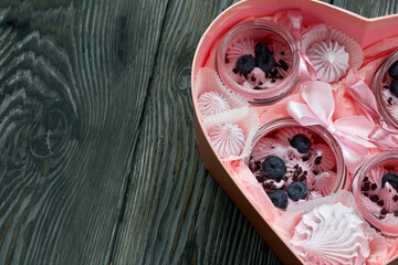 Zephyr in a jar, decorated with blueberries. Packaged in a heart-shaped gift box. On painted pine planks.