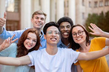 Group Of Students Posing Waving Hands And Gesturing V-Sign Outdoor