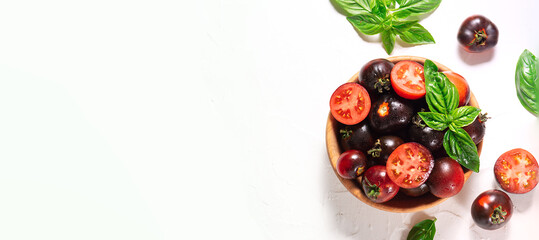 Fresh ripe tomatoes with basil leaves in the wooden bowl on white background top view. Long banner format.