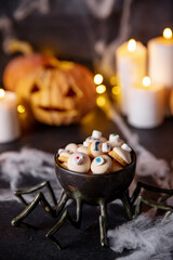 Stylized halloween sweet candies and cookies for holiday on dark background with cobwebs, pumpkins and candles