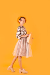 pretty caucasian girl getting ready for school. with yellow notebook in her hands. isolated on yellow background. copy space for text. full length