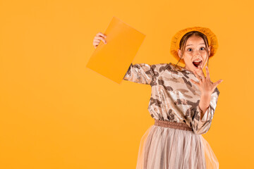 pretty caucasian girl looking surprised at camera with yellow notebook in her hands. isolated on yellow background. copy space for text.