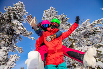 Loving couple woman and man having fun and fooling around in winter forest. Skier and snowboarder...