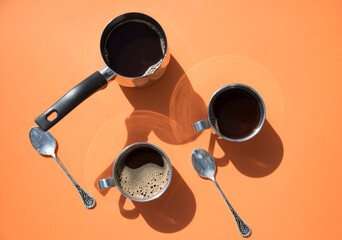 A Sunny morning, two cups of coffee and a pot of coffee stand on an orange background, the sun's...