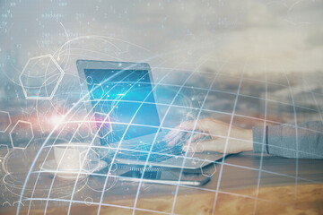 Double exposure of world map hologram with man working on computer on background. Concept of worldwideweb.