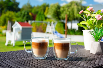 Two coffees on the table of sunny garden terrace