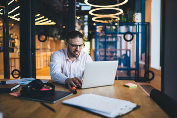 Positive male worker working on laptop in modern office