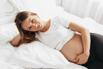 Happy pregnant woman lying on bed
