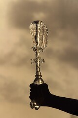 A hand pressing a water bottle exerting water out of the bottle and creating a vortex like effect .