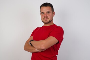 Young European man wearing red shirt over isolated yellow background happy face smiling with crossed arms looking at the camera. Positive person.