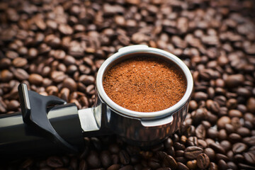 On the roasted dark aromatic coffee beans is a holder from the coffee maker, in which the filter is filled with ground coffee from these beans.