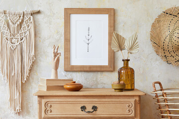 Stylish boho interior of living room with brown mock up poster frame, elegant accessories, flowers...