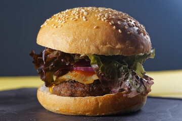 Juicy beef burger with cheese, bacon, tomato, lettuce, dressings, avocado, red onion and accompanied by french fries.