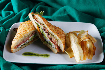 Beef baguette with tomato, lettuce, avocado and dressings accompanied by french fries.
