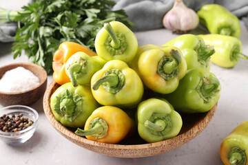 Organic bell peppers in a wooden plate on light gray background, Closeup