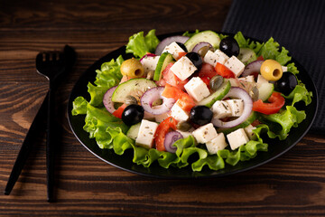 greek salad with olives and capers on a black plate