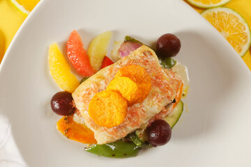 Roasted tilapia fish fillet with pumpkin, bell pepper, carrot, and orange, grapefruit, and lemon wedges.