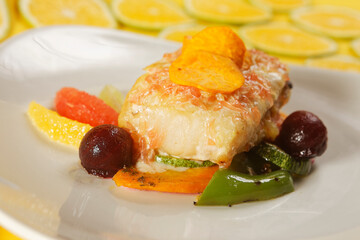 Roasted tilapia fish fillet with pumpkin, bell pepper, carrot, and orange, grapefruit, and lemon wedges.