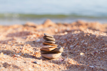 Fototapeta na wymiar Tower of flat stones on the beach by the sea.