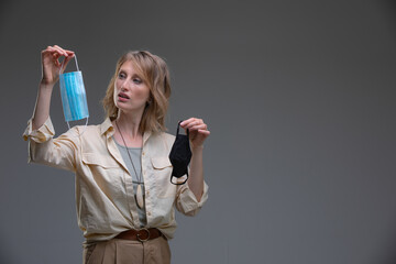 Head portrait attractive blond woman doing Difficult choice between surgical and tissue mask