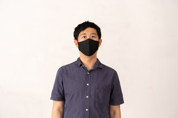 Studio shot of Asian man wearing protective face covering for safety during covid 19 pandemic, protective washable cloth mask, stopping the spread of the disease