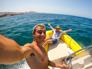 close up of teenager and young man taking a selfie with his mum in a boat in the middle of the sea...