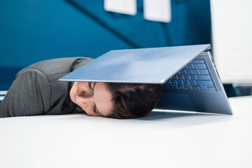 Exhausted business woman covered head with laptop. Tired female worker with a computer above her head.