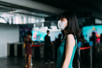 Asian woman wearing protective face covering to travel on metro during coronavirus pandemic, washable face mask, stopping the spread of the disease on public transport