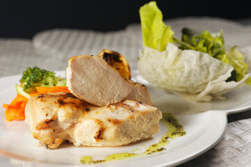Roasted chicken breast served with a lettuce salad garnished with broccoli, carrot, pumpkin, and lemon juice.