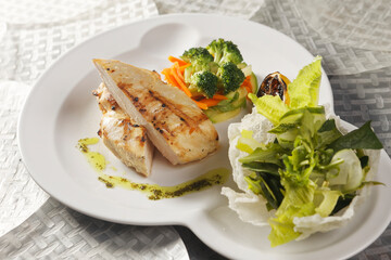 Roasted chicken breast served with a lettuce salad garnished with broccoli, carrot, pumpkin, and lemon juice.