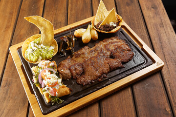 Grilled roast beef with golden chicken tacos, guacamole, chambray onions, and refried beans