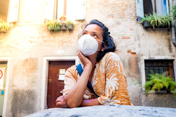 young woman wearing face mask looking up in a street of Venice in Italy. traveling and tourism industry during the corona virus pandemic and covid19 disease, affected by the global crisis