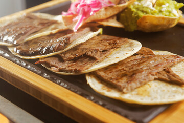 Grilled four tacos of sirloin steak served on comal with fire and accompanied by guacamole.