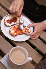 Breakfast closeup detail of a toast with cream and strawberry marmalade served with a cup of cold coffee in the morning