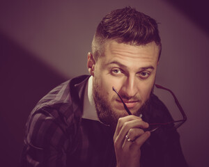 Portrait of young successful businessman posing in studio with glasses. image toned in warm colors in retro style