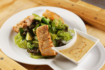 Tilapia fish fillet salad with lettuce, cabbage, kiwi, broccoli, and avocado.